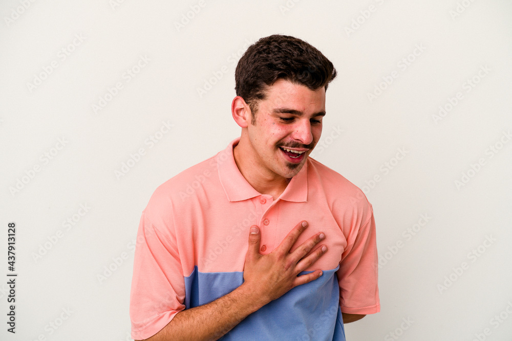 Young caucasian man isolated on white background laughing keeping hands on heart, concept of happiness. Young caucasian man isolated on white background laughing keeping hands on heart, concept of happiness.