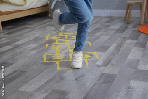 Little girl playing hopscotch at home, closeup photo