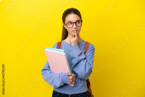 Student kid woman over isolated yellow background having doubts while looking up