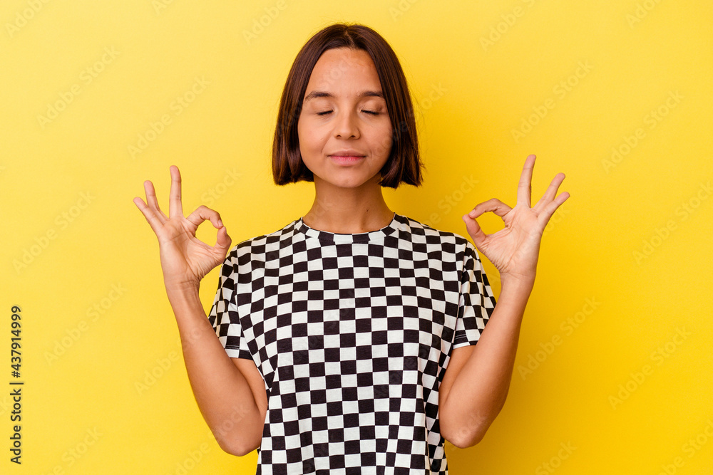 Young mixed race woman isolated on yellow background relaxes after hard working day, she is performing yoga. Young mixed race woman isolated on yellow background relaxes after hard working day, she is performing yoga.