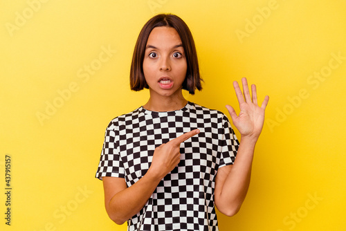 Young mixed race woman isolated on yellow background smiling cheerful showing number five with fingers. © Asier