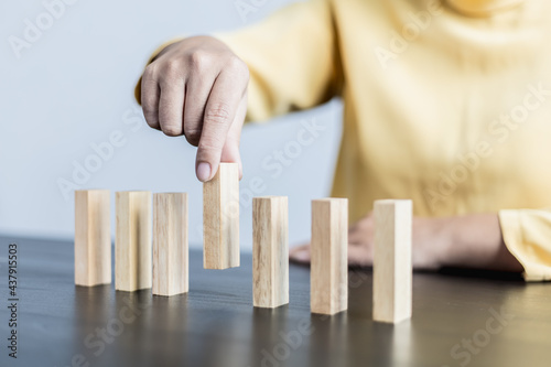 Businesswoman picking up a block of wood from a row, solving problems that arise during planned business operations, business problems caused by internal and external factors.