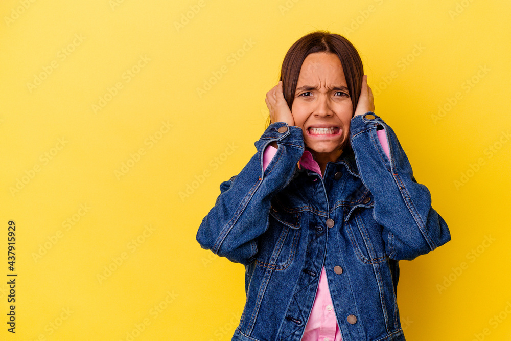 Young mixed race woman isolated on yellow background touching back of head, thinking and making a choice. Young mixed race woman isolated on yellow background touching back of head, thinking and making a choice.