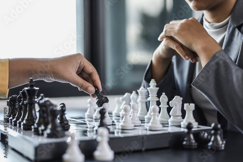 Two business women competitors playing chess board game, business competition concept, business plan to be the number one company, competitor analysis and problem solving. For always good results. photo