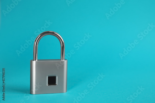 Modern padlock on light blue background. Space for text