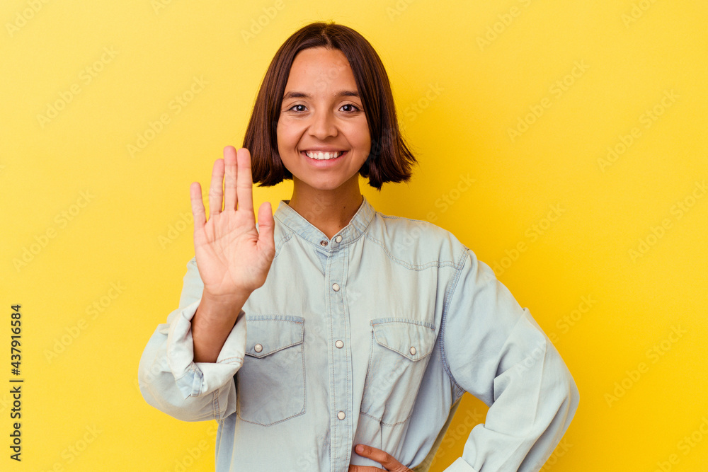 Young mixed race woman isolated on yellow background smiling cheerful showing number five with fingers.