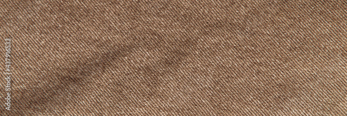 fabric grunge background, real cotton denim brown, wrinkled, frayed, close © BUSLIQ