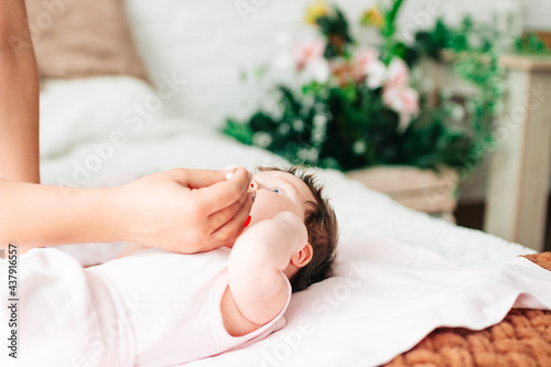 mom cleans the nose of a newborn baby with a cotton swab