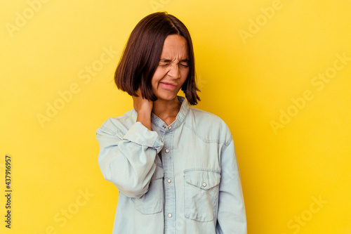 Young mixed race woman isolated on yellow background having a neck pain due to stress, massaging and touching it with hand.