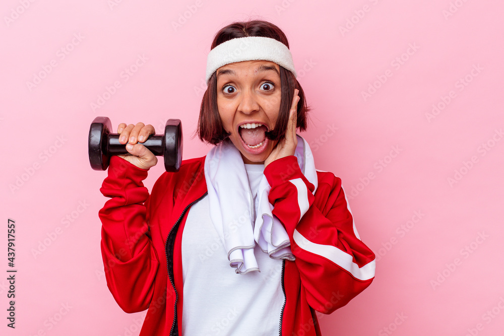 Young mixed race sport woman holding a weight isolated on pink background