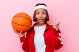 Young mixed race woman playing basketball isolated on pink background having an idea, inspiration concept.