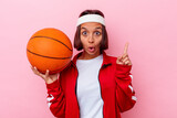 Young mixed race woman playing basketball isolated on pink background having some great idea, concept of creativity.