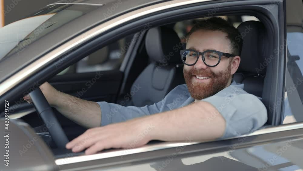 Happy man in eyeglasses sitting in car and looking at camera Happy man in eyeglasses sitting in car and looking at camera