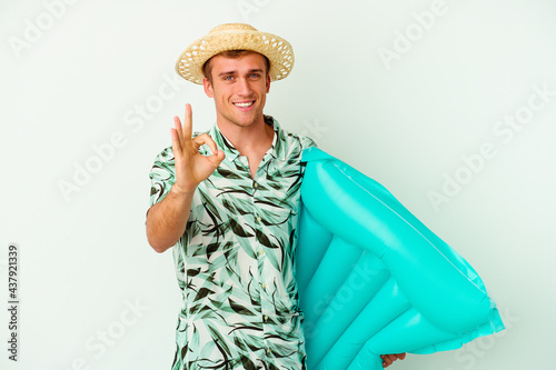 Young caucasian man wearing a summer clothes and holding a air mattress isolated on white background