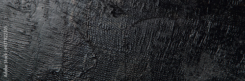 Photos Dark creative background - rough linen canvas unevenly covered with black primer, reflections of light