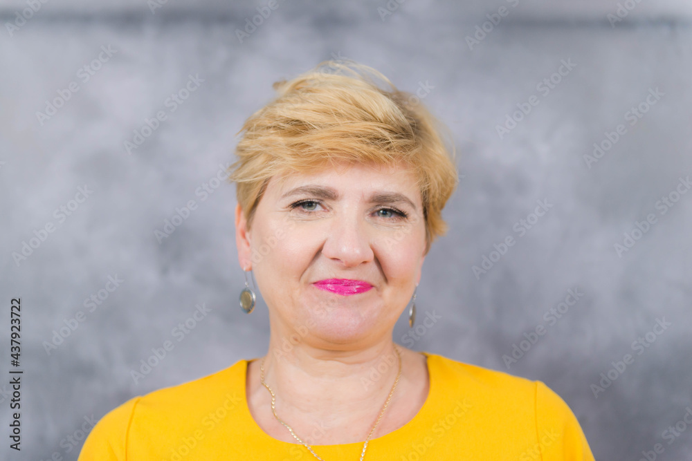 Ładna, elegancka kobieta w średnim wieku w żółtej sukience.
