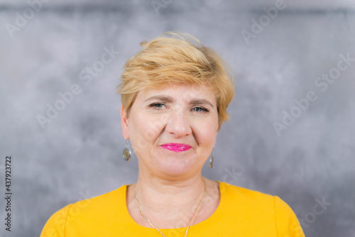 Obraz na płótnie Ładna, elegancka kobieta w średnim wieku w żółtej sukience. w salonie