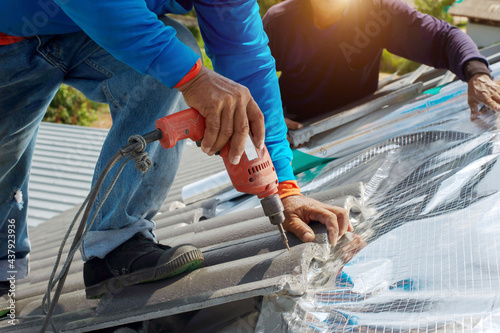 Construction worker install new roof,Roofing tools,Electric drill used on new roofs with Metal Sheet.