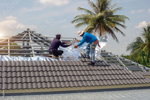 Construction workers install roof tiles on top roof, roof structure of building on construction site, residential building construction concept.