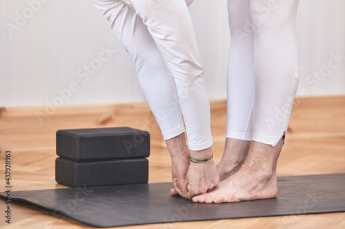 Closed portrait with no visible face of Forward Bend Yoga pose. yoga mat and smooth background