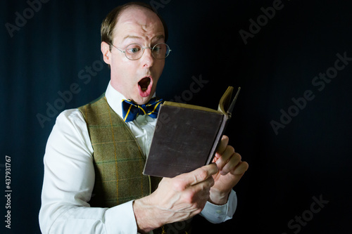 Portrait of Man in Vest and Bow Tie Reading Exciting Book. Concept of Teacher or Professor in Love with Literature and Reading photo