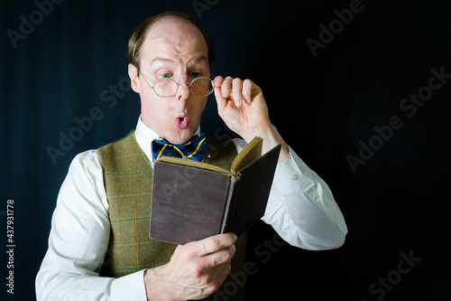 Portrait of Man in Vest and Bow Tie Reading Exciting Book. Concept of Teacher or Professor in Love with Reading and Literature. photo