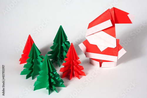 Origami santa claus with red and green trees isolated on white background.