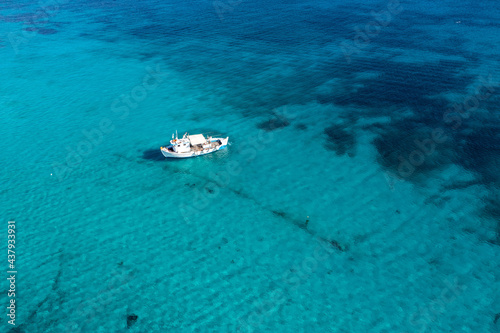 Greece, Cyclades. Aerial drone view of a fishing boat on turquoise color sea water