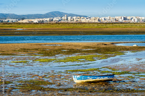Boat by Ria Formosa wetlands with Faro in the background, Algarve, Portugal