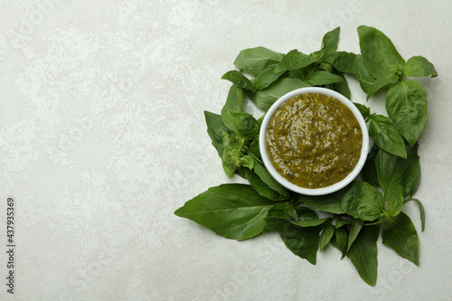 Bowl of Pesto sauce and basil on white textured background