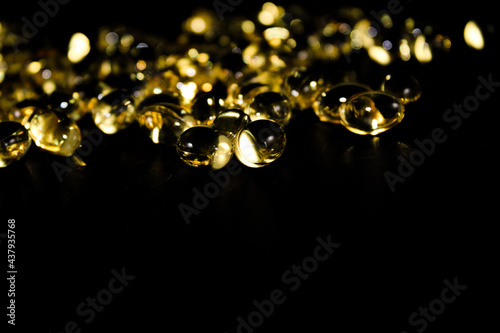 Cod liver oil capsules close up, abstract, isolated on black background