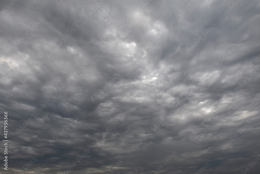 Background consists of clouds in autumn sky. Sky is covered with large gray clouds. Natural texture. Sky before heavy rain. Natural background symbolizing sadness and loneliness. Background consists of clouds in autumn sky. Sky is covered with large gray clouds. Natural texture. Sky before heavy rain. Natural background symbolizing sadness and loneliness.