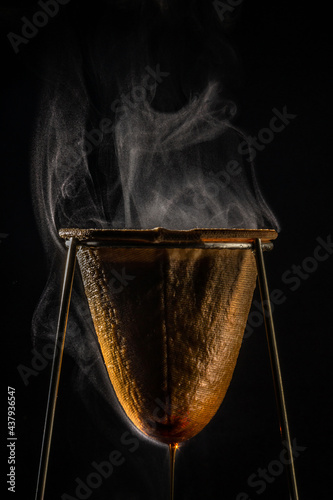 Café sendo coado no coador de tecido e vapor subindo, com fundo preto. photo