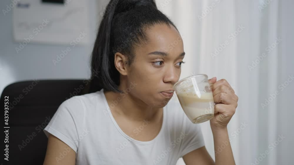 Close-up portrait of serious young woman drinking morning coffee in home office indoors. Beautiful attractive slim African American freelancer thinking planning work day. Lifestyle and freelance Close-up portrait of serious young woman drinking morning coffee in home office indoors. Beautiful attractive slim African American freelancer thinking planning work day. Lifestyle and freelance