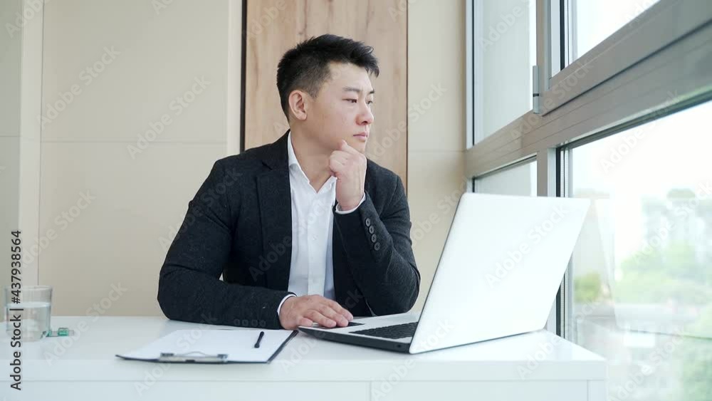 close-up portrait asian pensive young office worker man at workplace. face a serious male business manager in formal suit thinking about solving a problem. Businessman at desk with computer or laptop close-up portrait asian pensive young office worker man at workplace. face a serious male business manager in formal suit thinking about solving a problem. Businessman at desk with computer or laptop