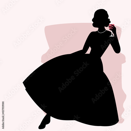 Silhouette of woman sitting on an armchair and dressed in elegant retro style dress holding a glass of red wine