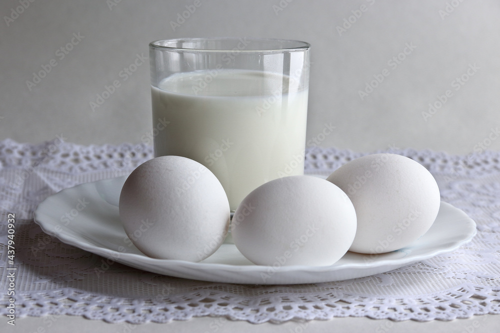 Morning rustic breakfast with milk and eggs in light colors. A glass of milk and eggs in a plate on an openwork napkin. Morning rustic breakfast with milk and eggs in light colors. A glass of milk and eggs in a plate on an openwork napkin.