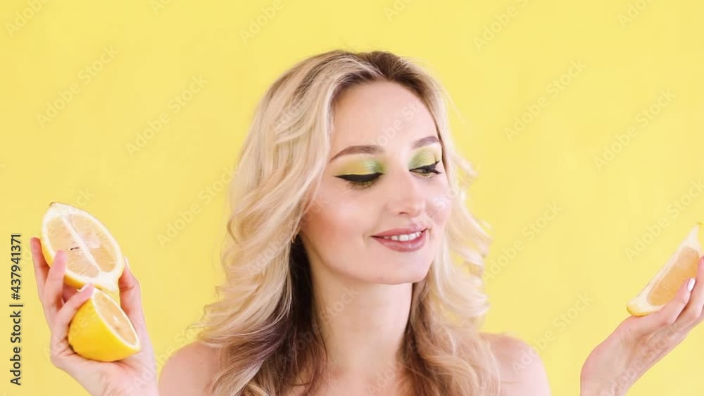 Woman with hairstyle and make up posing with lemons on yellow background. Woman with hairstyle and make up posing with lemons on yellow background.
