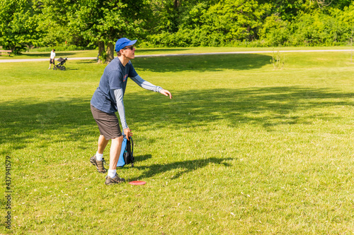 Disc golf is a flying disc sport in which players throw a disc at a target; it is played using rules similar to golf, this player is enjoying a early summer morning on a course in Toronto.