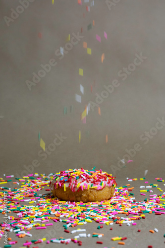 Sprinkles falling on white frosting donut
