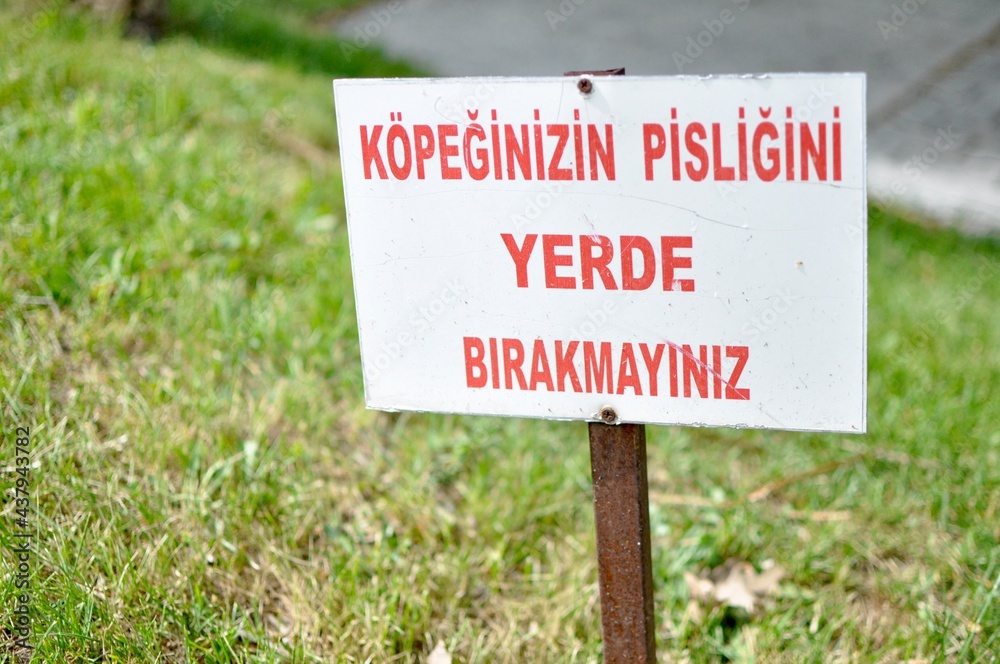 Clean Up After Your Dog sign in Turkish at the park. 