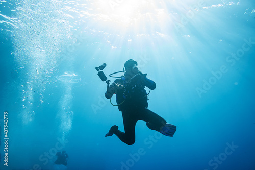 diver with equipment for underwater shooting underwater on a blue background 