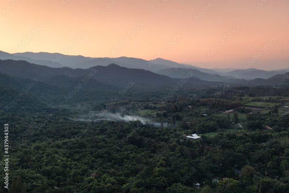 Scenery of colorful sky on green forest and mountain range in countryside