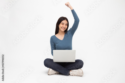 Happy young Asian woman sitting on the floor with crossed legs and rasing hand up and using laptop computer isolated on white background, Full body © comzeal