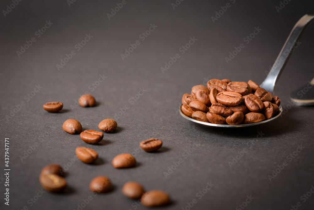 Side view of Roasted coffee beans served in silver vintage stainless steel spoon with scattered beans on dark background. High quality organic aroma seeds. Copy space text image
Side view of Roasted coffee beans served in silver vintage stainless steel spoon with scattered beans on dark background. High quality organic aroma seeds. Copy space text image