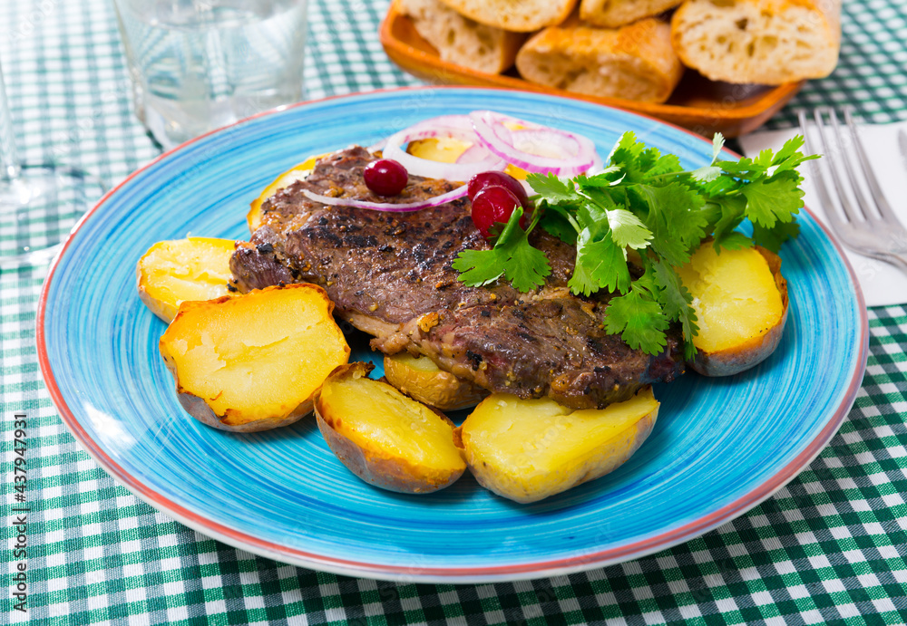 Tasty beef steak with baked potatoes served at plate with greens