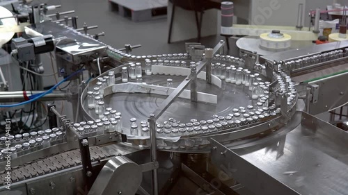 Vaccine Mass Production vaccine in Laboratory. Medicine bottles pharmaceutical factory. Automated production of ampoules with medicine Empty glass bottles on automatic production line machine conveyor
