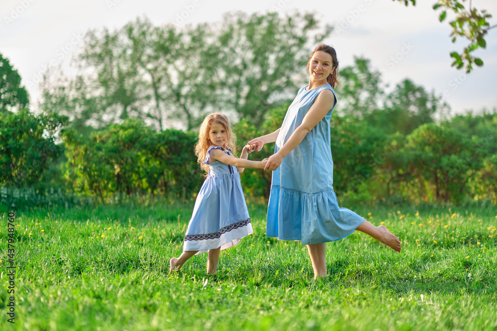 Naklejka premium nature scene with family outdoor lifestyle. Mother and little daughter playing together in a park. Happy family concept. Happiness and harmony in family life.