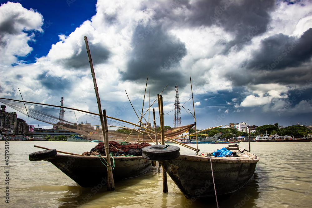 Fototapeta premium Traditional fishing boat on the riverbank under the cloudy sky, This image captured on September 21, 2018, from Narayangonj, Bangladesh, South Asia