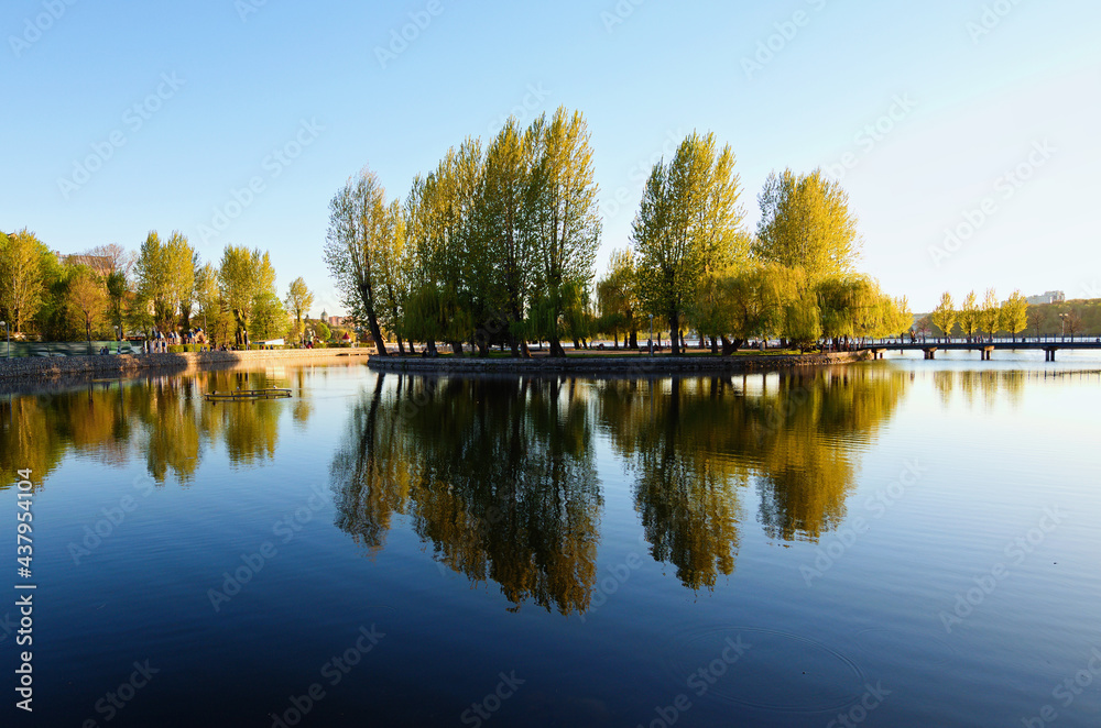 Beautiful landscape photo of embankment in the Taras Shevchenko Park in Ternopil. Trees reflected in tranquil water. Magic sunset view. Ternopil, Ukraine